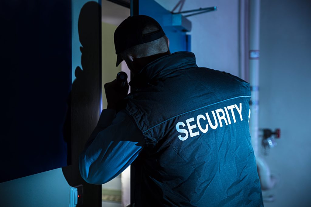 rear view of a male security officer in uniform using flashlight
