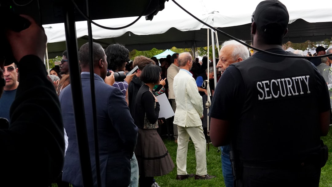 security-guard-watches-over-a-gathering-under-a-tent-yq9afeawqeo